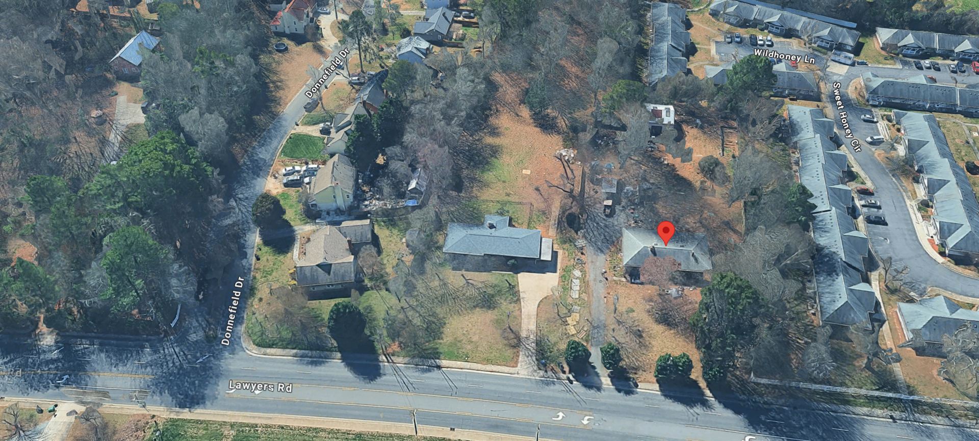 Oblique aerial view of 7214 Lawyers Rd, Charlotte NC. The parcel is marked at center-right with frontage on Lawyers Road; the Wildhoney Lane and Sweet Honey Circle townhome community adjoins the parcel at the right of frame, and Donnefield Drive enters from the left.